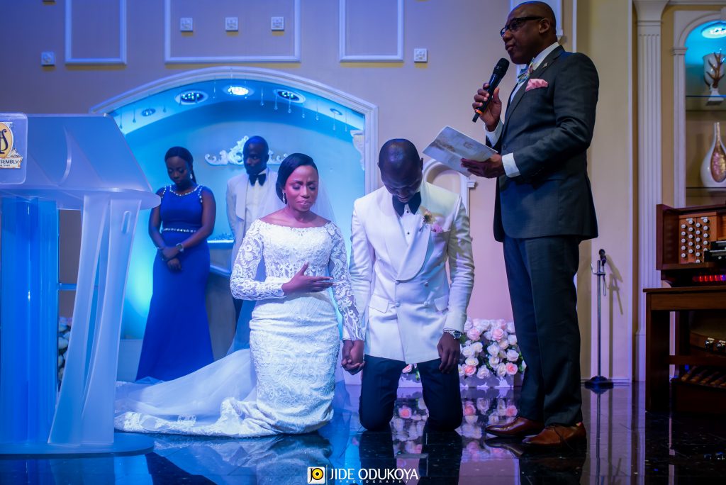 Kemi and Pelu kneeling in prayer during their church wedding ceremony